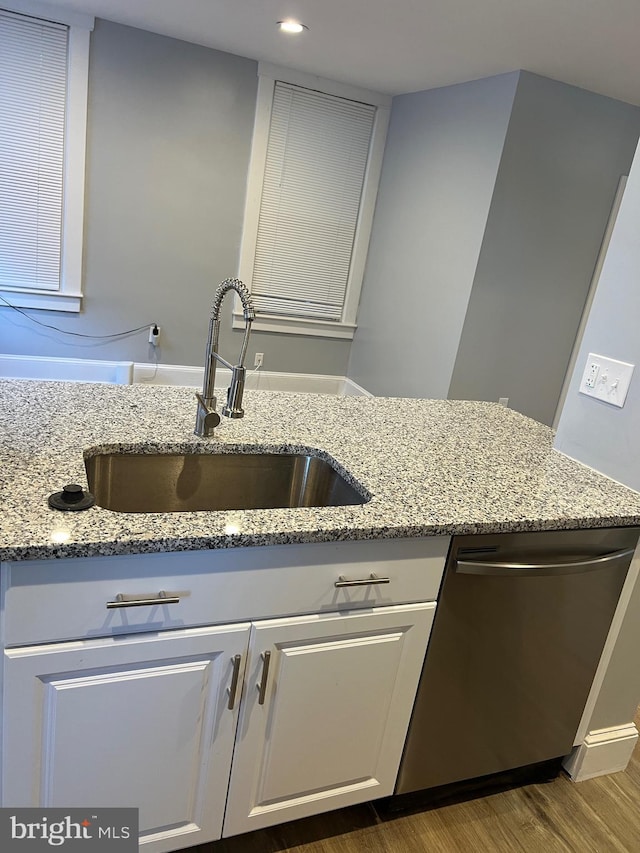 kitchen with sink, dishwasher, light stone counters, and wood-type flooring