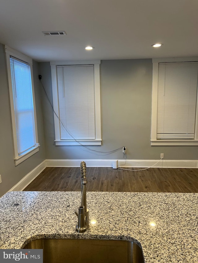 interior details featuring sink, light stone countertops, and dark hardwood / wood-style floors