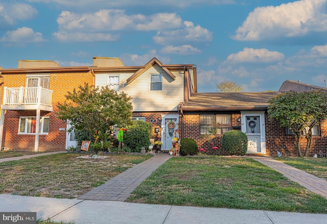 townhome / multi-family property featuring a front yard and a balcony