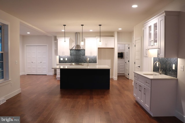 kitchen with white cabinetry, sink, wall chimney exhaust hood, dark hardwood / wood-style flooring, and decorative light fixtures