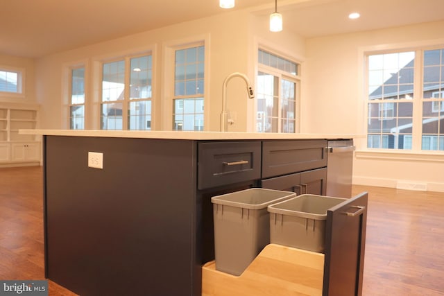 kitchen featuring hardwood / wood-style floors, a kitchen island, hanging light fixtures, and a healthy amount of sunlight