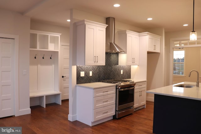 kitchen with wall chimney exhaust hood, stainless steel gas range oven, white cabinetry, and sink