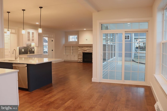 kitchen featuring a kitchen island with sink, sink, dishwasher, white cabinetry, and hanging light fixtures