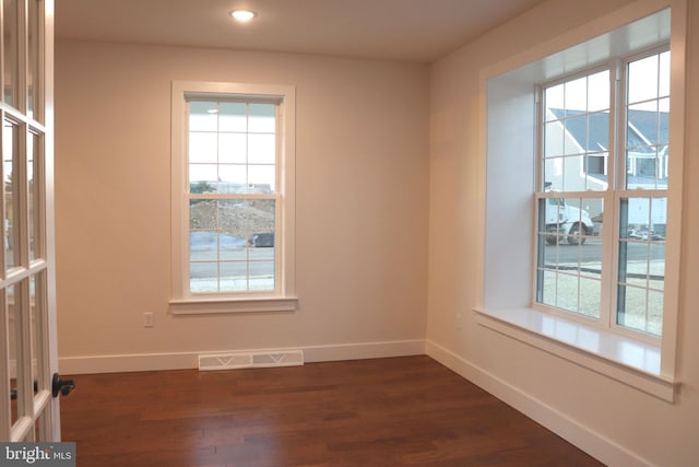 unfurnished room with plenty of natural light and dark hardwood / wood-style flooring