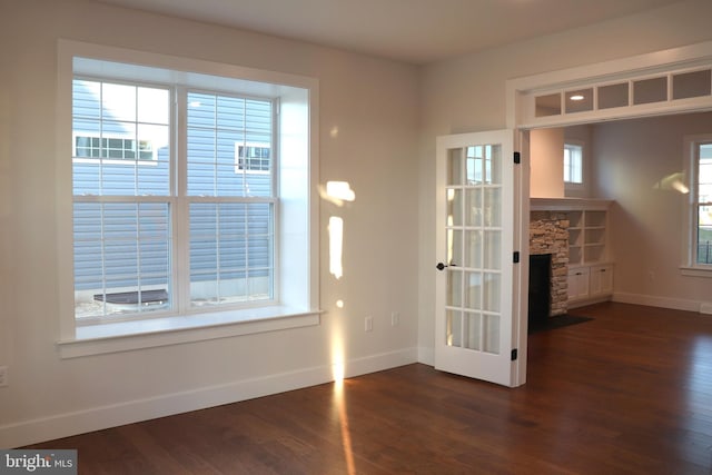 spare room with a fireplace and dark wood-type flooring