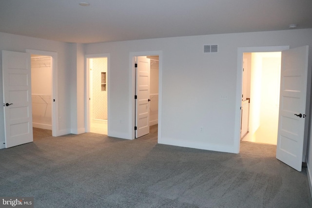 unfurnished bedroom featuring carpet flooring, a spacious closet, connected bathroom, and a closet