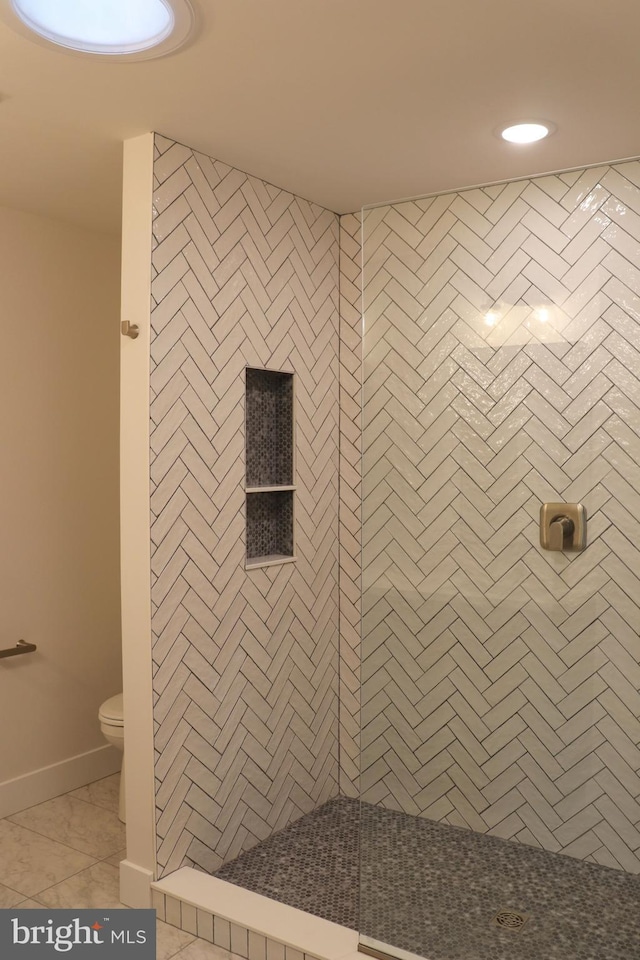 bathroom featuring tile patterned flooring, tiled shower, and toilet