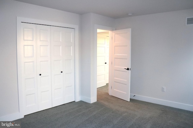 unfurnished bedroom with dark carpet and a closet