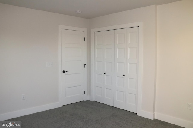 unfurnished bedroom featuring a closet and dark colored carpet