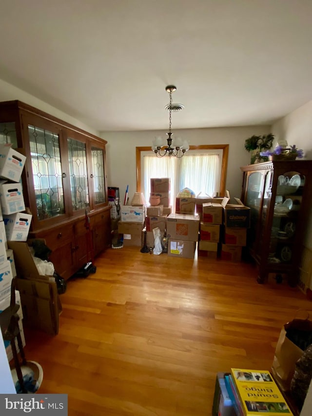 dining area with light hardwood / wood-style floors and a notable chandelier