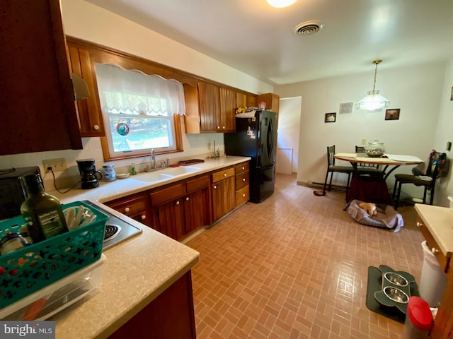 kitchen with sink, black fridge, and hanging light fixtures