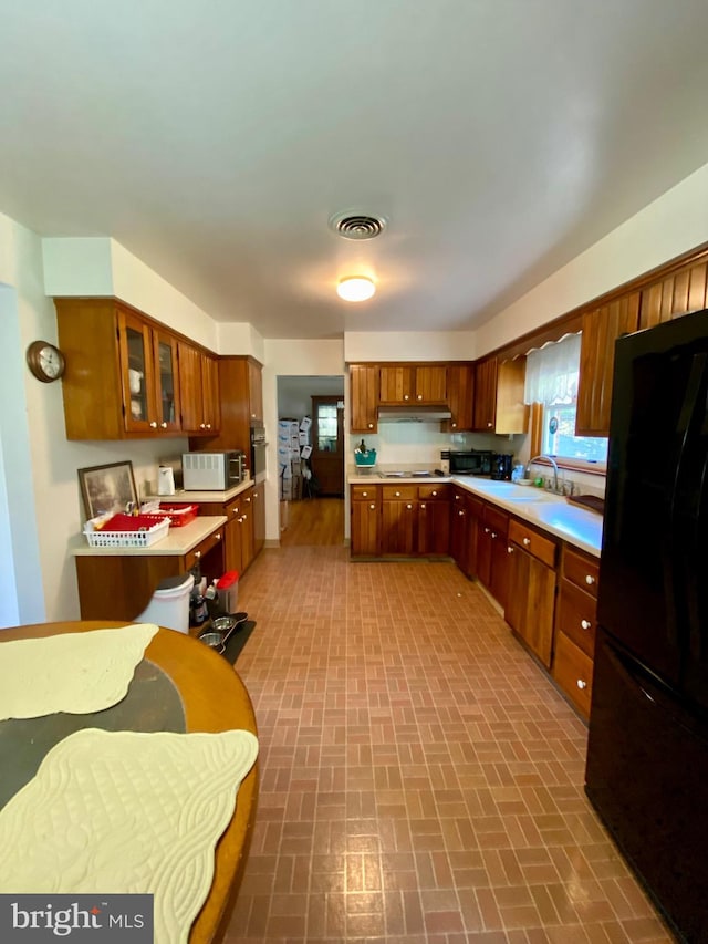 kitchen featuring stovetop, sink, and black fridge