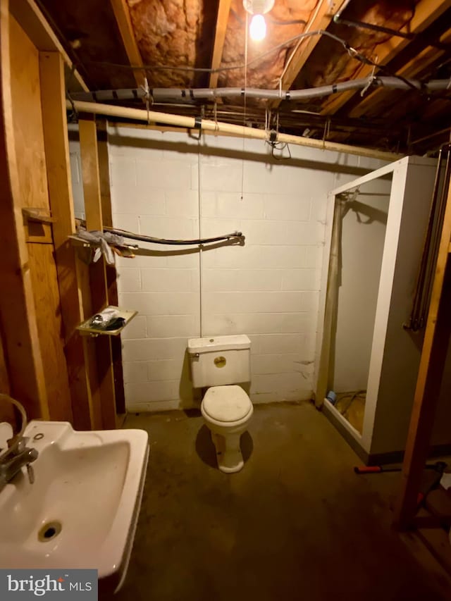 bathroom featuring sink, toilet, a shower with shower door, and concrete floors