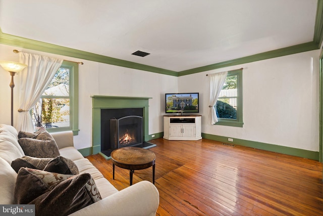 living room with ornamental molding, wood-type flooring, and plenty of natural light