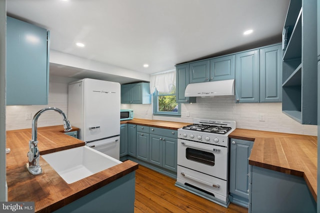 kitchen featuring hardwood / wood-style floors, butcher block counters, blue cabinets, and white appliances