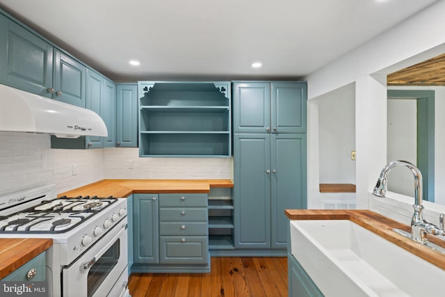 kitchen featuring a sink, butcher block countertops, under cabinet range hood, gas range gas stove, and tasteful backsplash