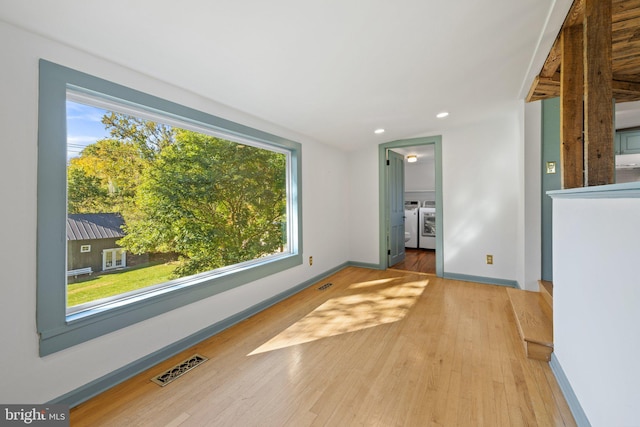 unfurnished living room featuring a wealth of natural light, separate washer and dryer, visible vents, and wood finished floors