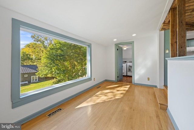 unfurnished living room with light wood-type flooring, a healthy amount of sunlight, and separate washer and dryer