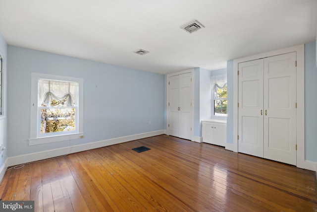 unfurnished bedroom with baseboards, visible vents, and wood-type flooring
