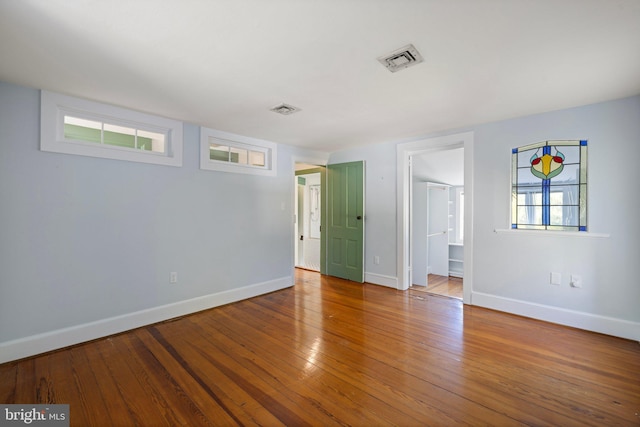 empty room featuring baseboards, visible vents, and hardwood / wood-style flooring