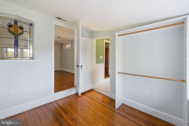 empty room with baseboards, hardwood / wood-style floors, and visible vents