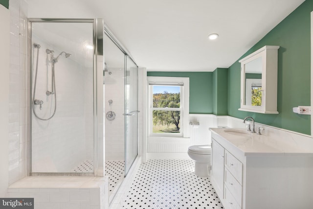 full bath with vanity, a stall shower, toilet, and wainscoting