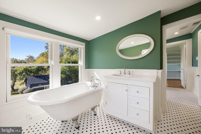 full bath with wainscoting, visible vents, vanity, a decorative wall, and a freestanding tub