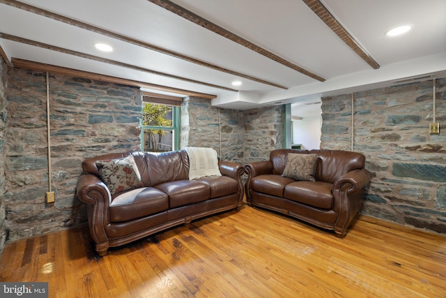 living room featuring beamed ceiling and light hardwood / wood-style floors