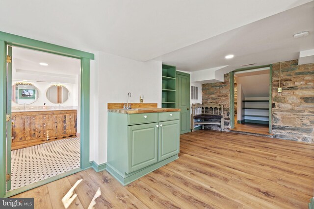interior space with green cabinets, a fireplace, light wood-style flooring, and open shelves