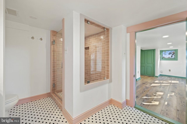 bathroom featuring tiled shower, hardwood / wood-style floors, and toilet