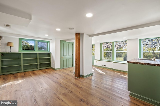 interior space with a sink, wood-type flooring, plenty of natural light, and visible vents