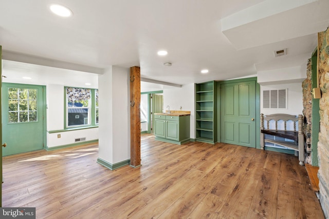 unfurnished living room featuring sink and light hardwood / wood-style floors