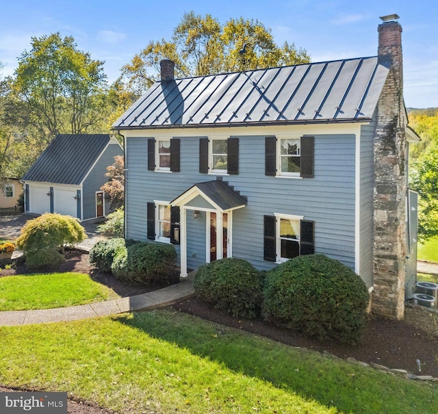 colonial-style house with a chimney, metal roof, and a standing seam roof