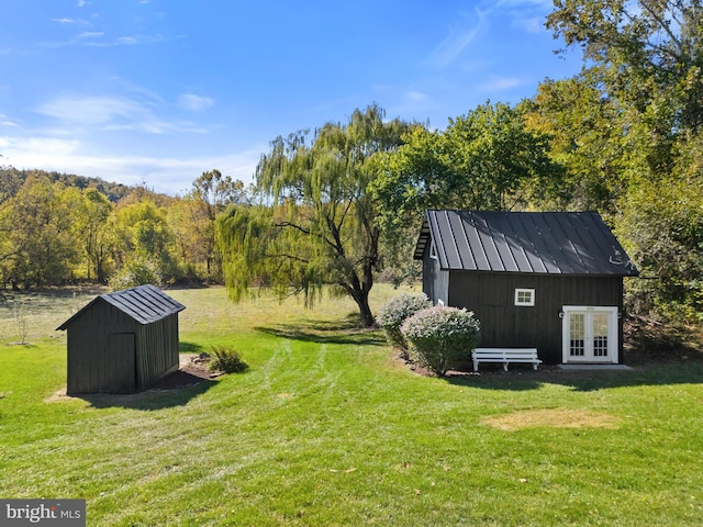 view of yard featuring a storage shed, french doors, and an outbuilding