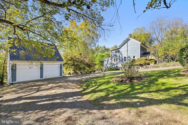 view of home's exterior with a detached garage, an outbuilding, and a lawn