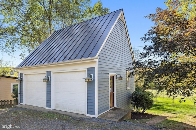 view of property exterior with metal roof, a detached garage, a standing seam roof, and an outbuilding