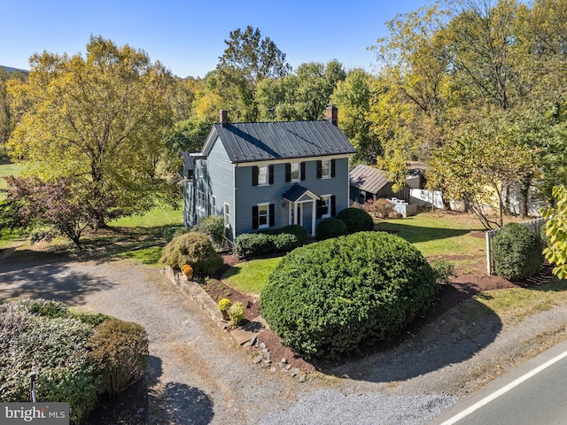 colonial-style house featuring a chimney and metal roof