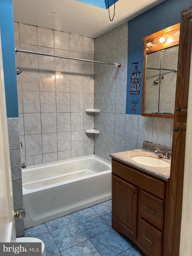 full bathroom with toilet, vanity, tile walls, and tiled shower / bath