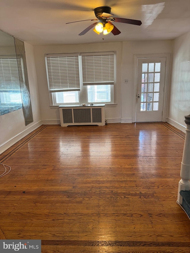 empty room featuring ceiling fan, hardwood / wood-style flooring, a wealth of natural light, and radiator