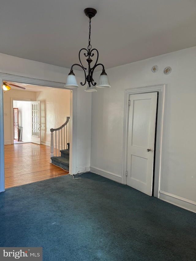 unfurnished room featuring ceiling fan with notable chandelier and hardwood / wood-style flooring