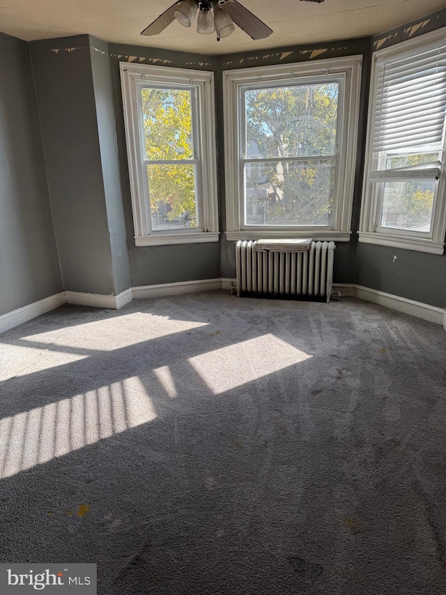 carpeted spare room featuring ceiling fan and radiator heating unit