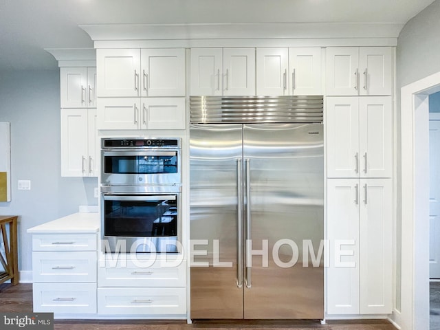 kitchen with dark wood-style flooring, light countertops, appliances with stainless steel finishes, and white cabinetry