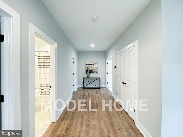 hall featuring light wood-style floors, baseboards, and recessed lighting