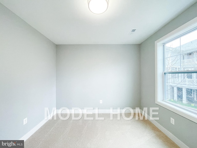 empty room featuring visible vents, baseboards, and carpet