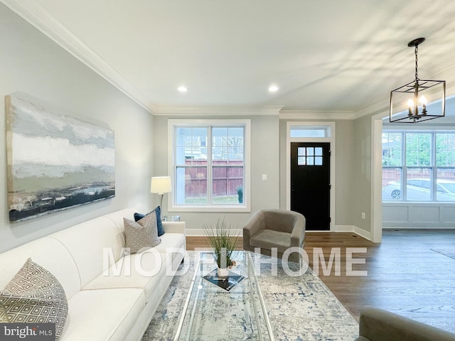 living room featuring baseboards, ornamental molding, a chandelier, recessed lighting, and wood finished floors