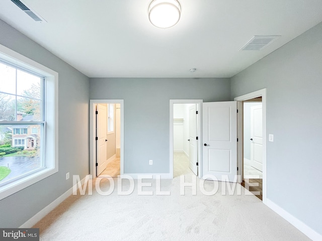 unfurnished bedroom with carpet, visible vents, baseboards, and ensuite bath