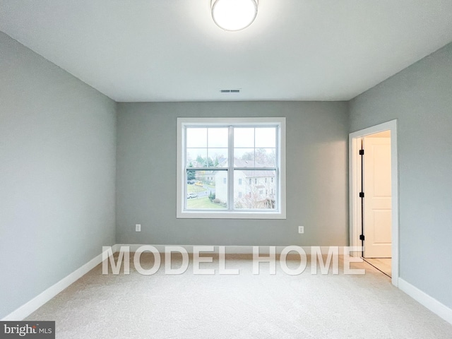 carpeted spare room featuring visible vents and baseboards