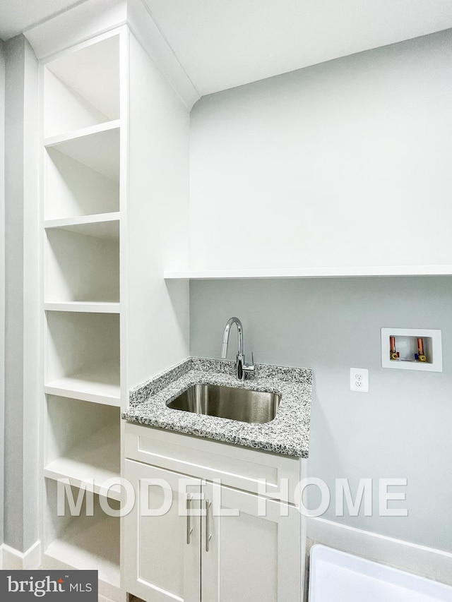 clothes washing area featuring a sink, hookup for a washing machine, and cabinet space