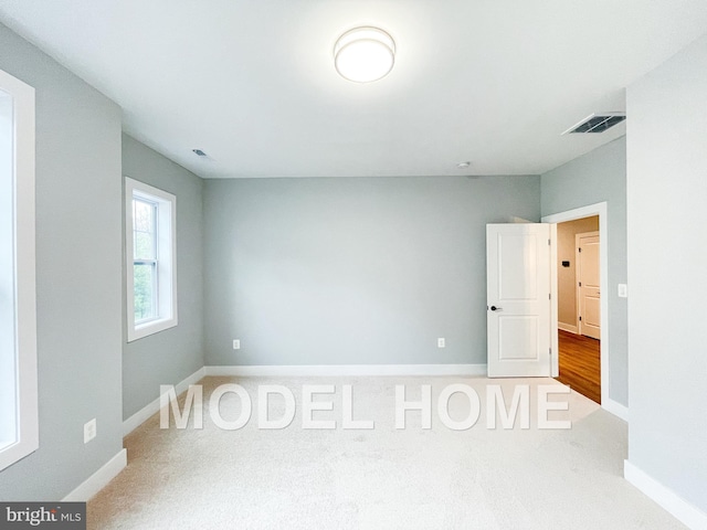 carpeted empty room featuring visible vents and baseboards
