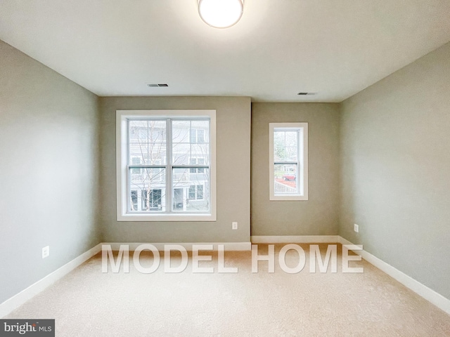 carpeted spare room with visible vents and baseboards